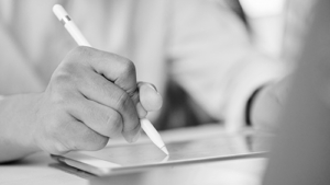 Closeup of man holding stylus and working on modern tablet in daylight